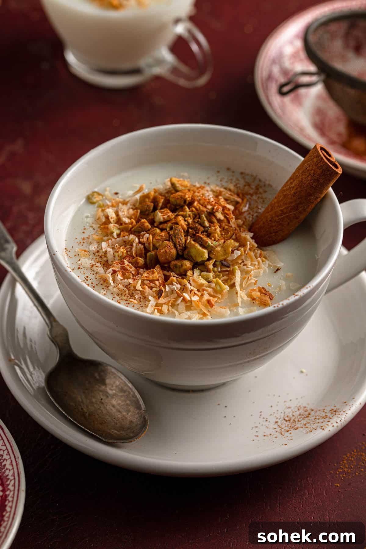Sahlab: Creamy Middle Eastern Pudding Recipe for Cozy Nights 2 A mug filled with warm milk pudding and topped with shredded coconut, chopped pistachios and cinnamon.