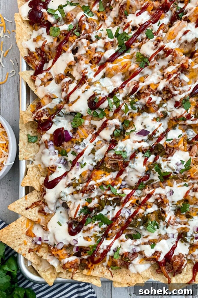Sheet Pan BBQ Chicken Nachos for Crowd-Friendly Game Night 4 oven baked BBQ chicken nachos drizzled with BBQ sauce