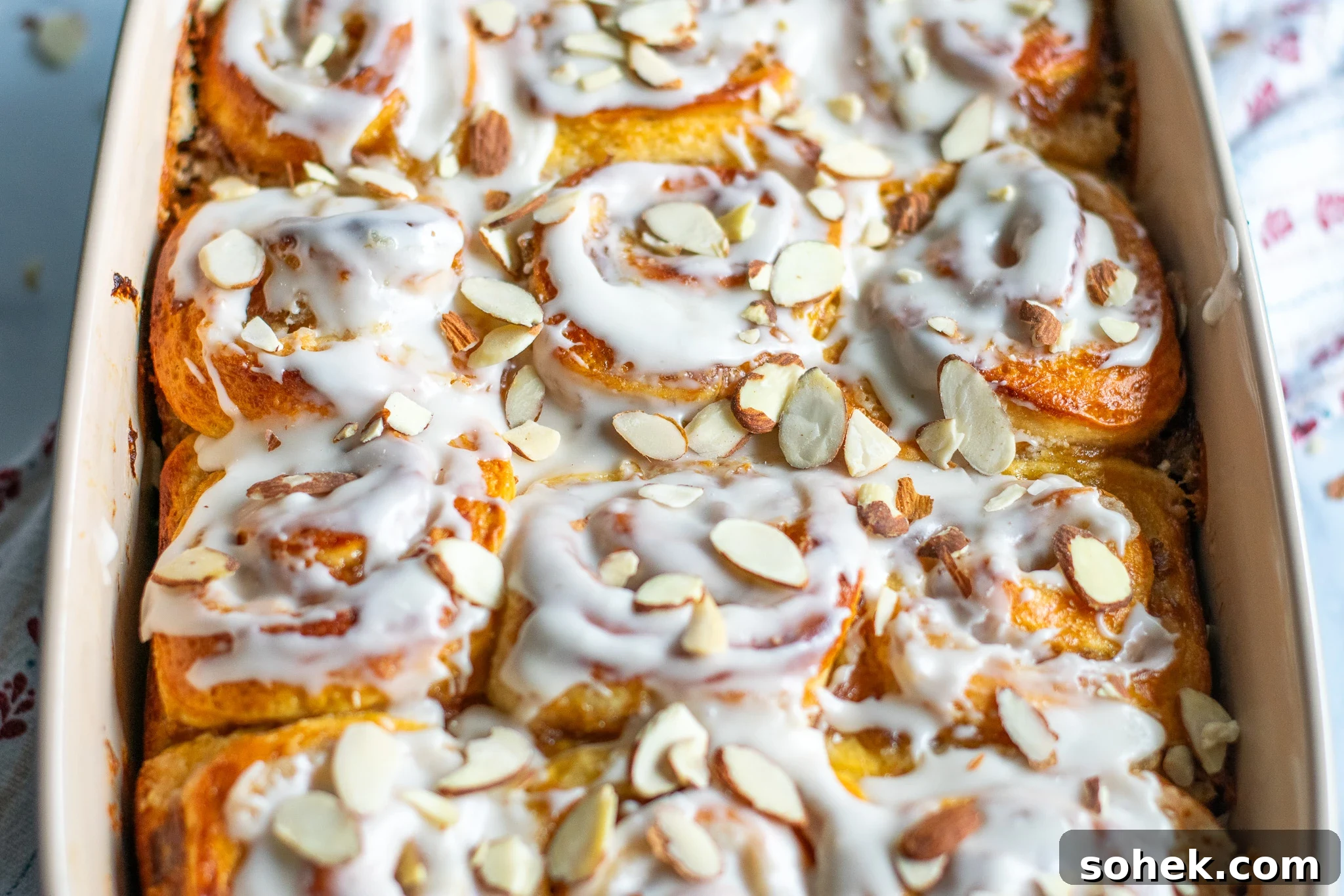 Rhubarb Almond Buns (Rabarber Scones with Almond Filling) 11 Rhubarb and marzipan swirls in a pan with icing and topped with sliced almonds.