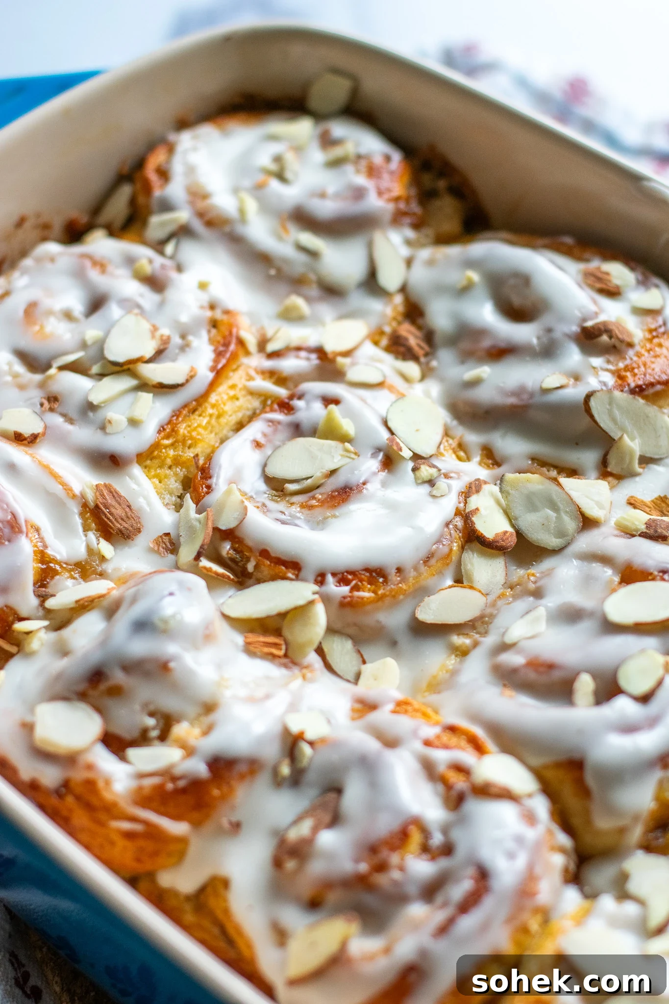 Rhubarb Almond Buns (Rabarber Scones with Almond Filling) 4 Rhubarb and marzipan swirls in a pan with icing and topped with sliced almonds.