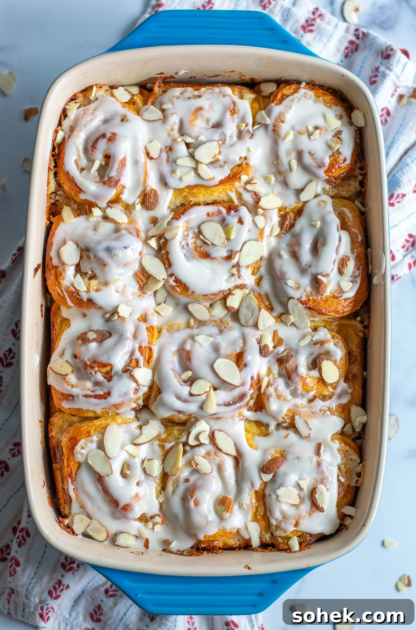 Rhubarb Almond Buns (Rabarber Scones with Almond Filling) 6 Rhubarb and marzipan swirls in a pan with icing and topped with sliced almonds.