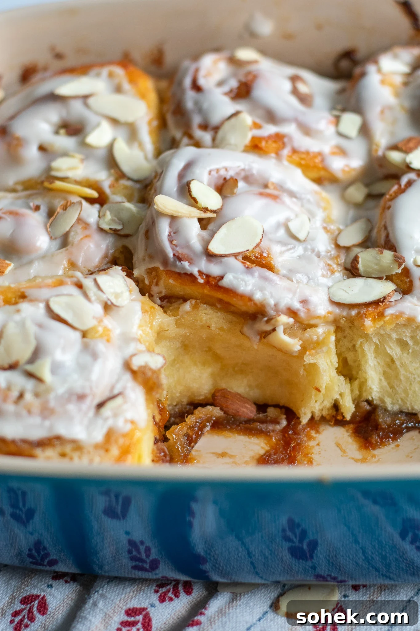Rhubarb Almond Buns (Rabarber Scones with Almond Filling) 8 Rhubarb and marzipan swirls in a pan with icing and topped with sliced almonds.