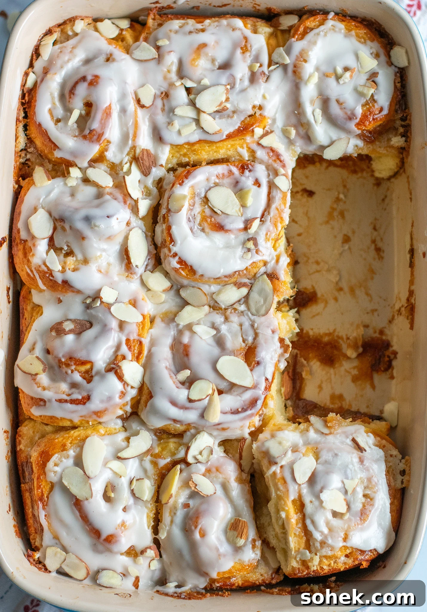 Rhubarb Almond Buns (Rabarber Scones with Almond Filling) 10 Rhubarb and marzipan swirls in a pan with icing and topped with sliced almonds.