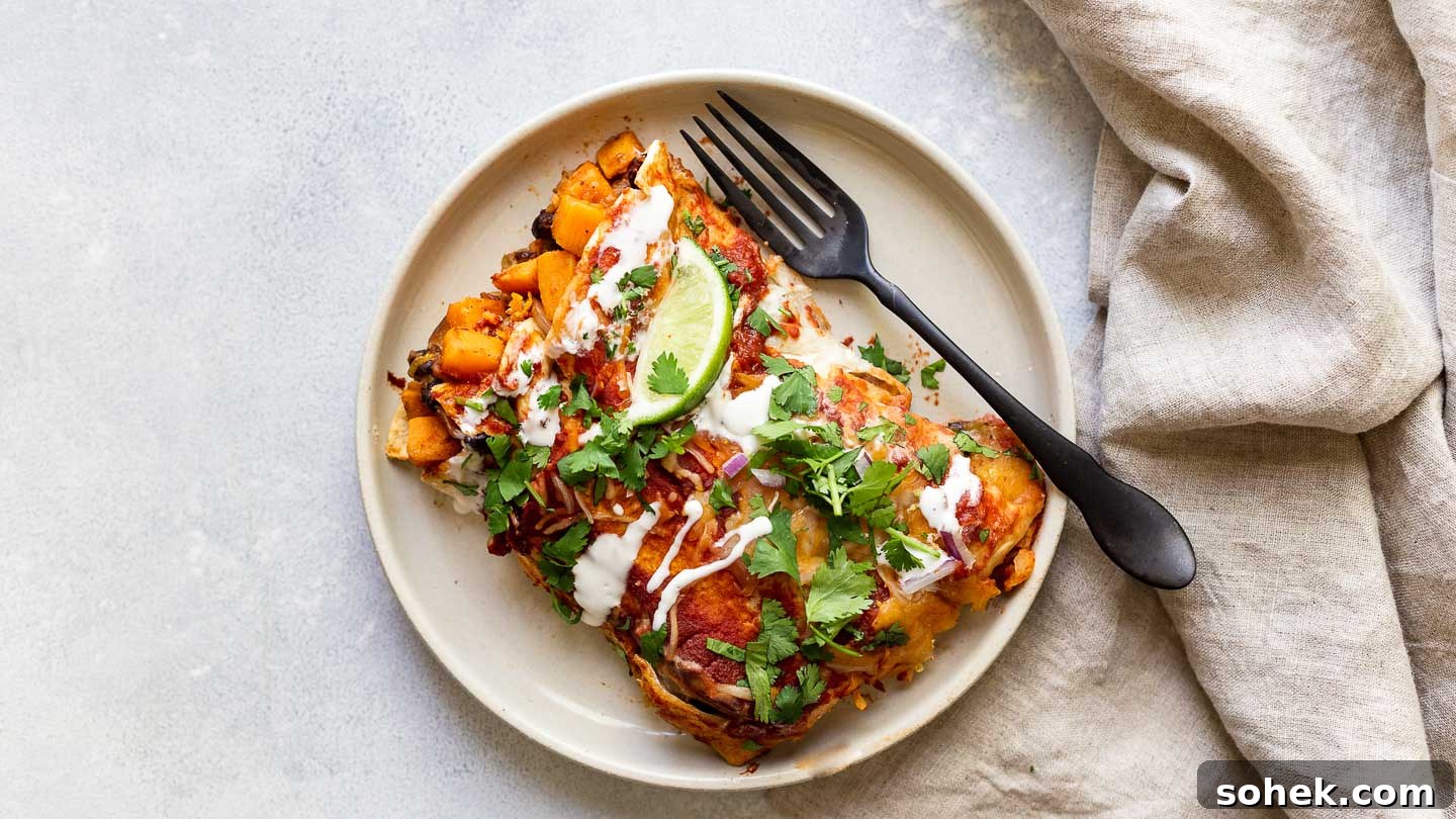 Sweet Potato Enchilada Casserole Recipe — Layered Comfort Bake 5 Two sweet potato enchiladas on a plate with a fork and napkin.