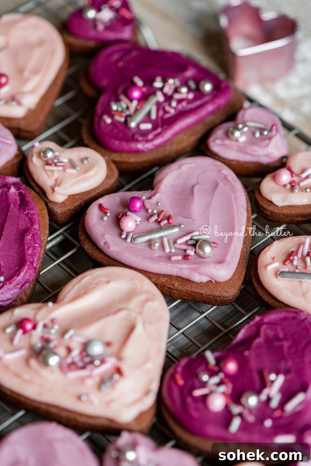 Chocolate Cut-Out Cookies: Decadent Cocoa Sugar Cookies for Decorating 3 Angled image of decorated chocolate cut out sugar cookies on a wire cooling rack on light wood colored background | All Images © Beyond the Butter®