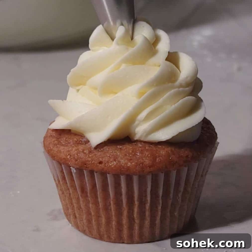 Strawberry Crunch Cupcakes Recipe with Crispy Topping 11 Piping creamy vanilla frosting onto a freshly baked strawberry crunch cupcake, finalizing the dessert.