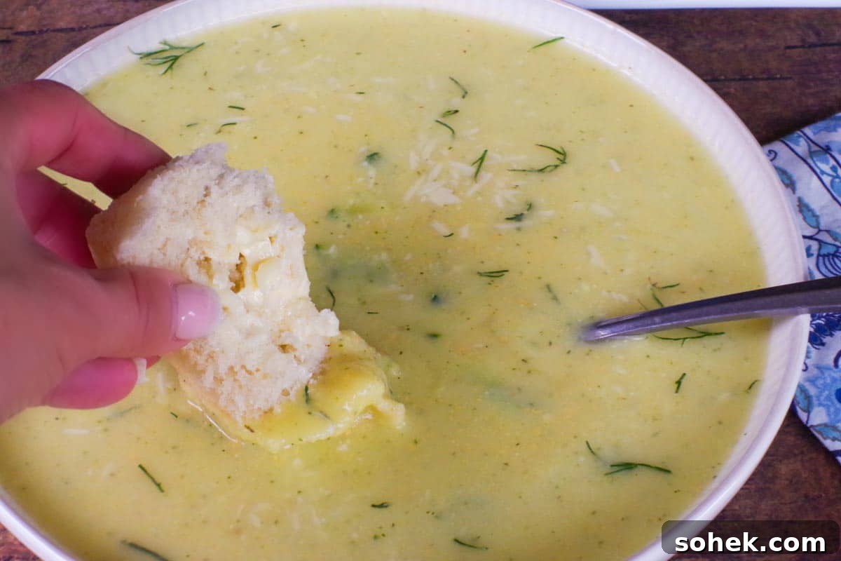 Zucchini and Potato Soup with Fresh Dill Recipe 12 buttered granny bun being dipped into a bowl of Zucchini Potato Soup