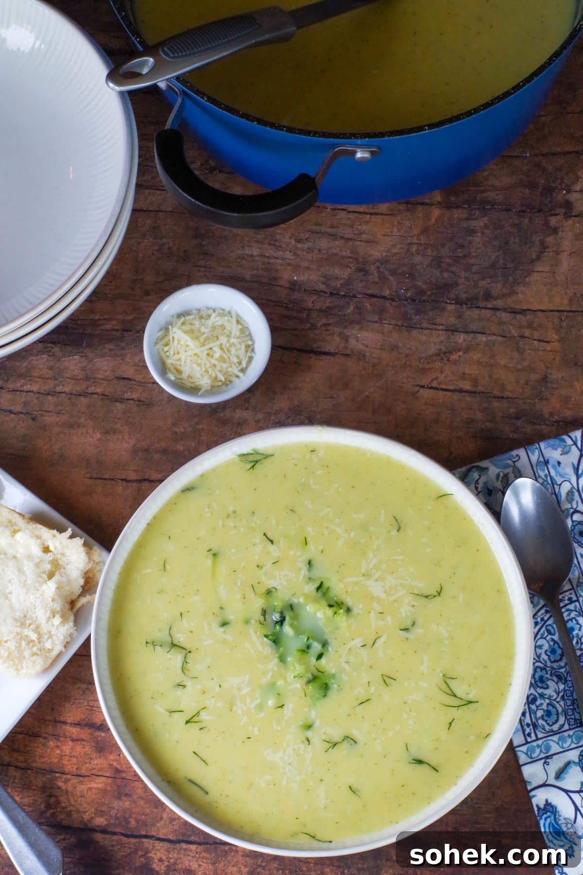 Zucchini and Potato Soup with Fresh Dill Recipe 10 Zucchini Potato soup in a beige bowl with blue paisley napkin and spoon on the side and a dish of parmesan cheese in background