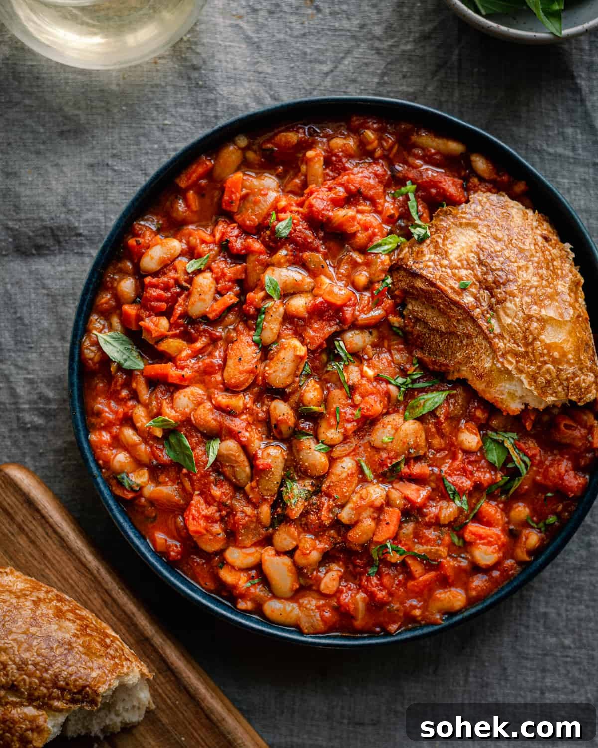 livornese stewed beans in a bowl bowl with a piece of bread on blue tablecloth