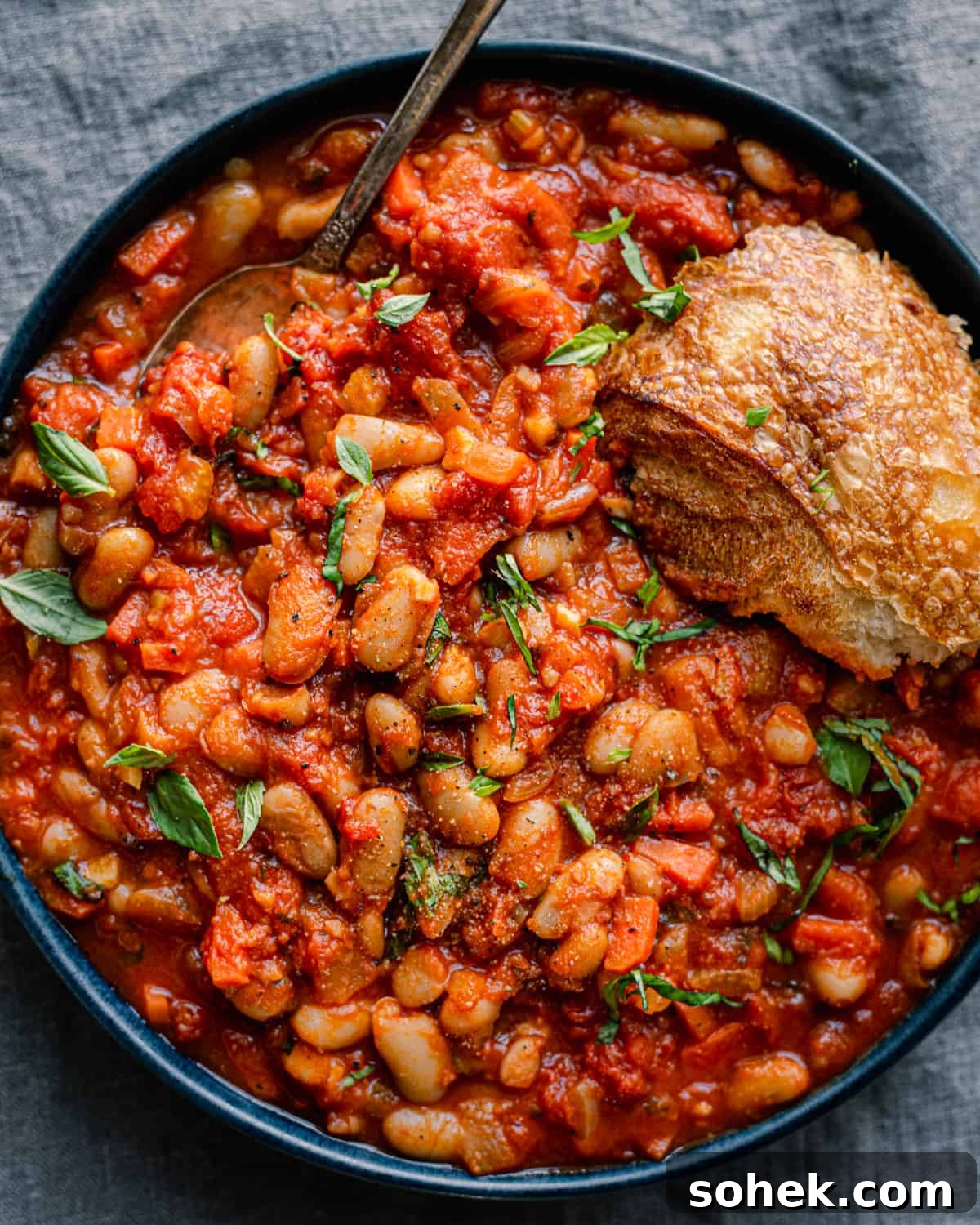 livornese stewed beans in a bowl bowl with a piece of bread on blue tablecloth