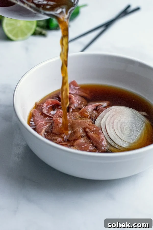 pho broth being poured over top steak and sliced onions