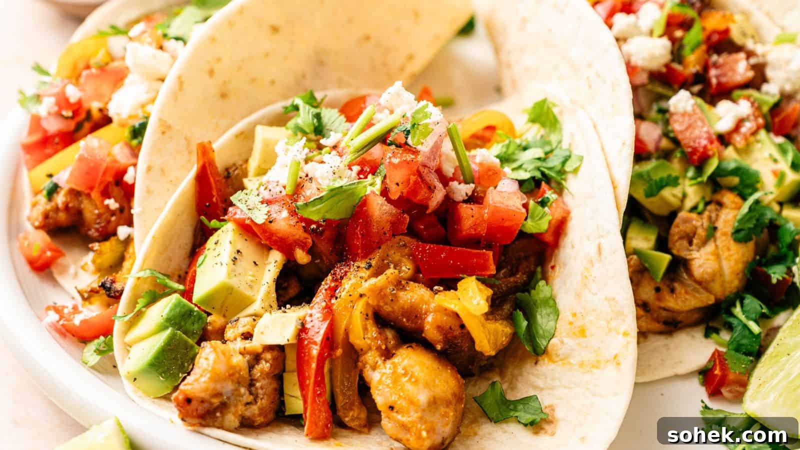 33 Quick Chicken Dinners for Busy Nights When You’re Tired but Hungry 22 Three soft tacos filled with seasoned chicken, diced avocado, chopped tomatoes, crumbled cheese, and fresh cilantro on a white plate.