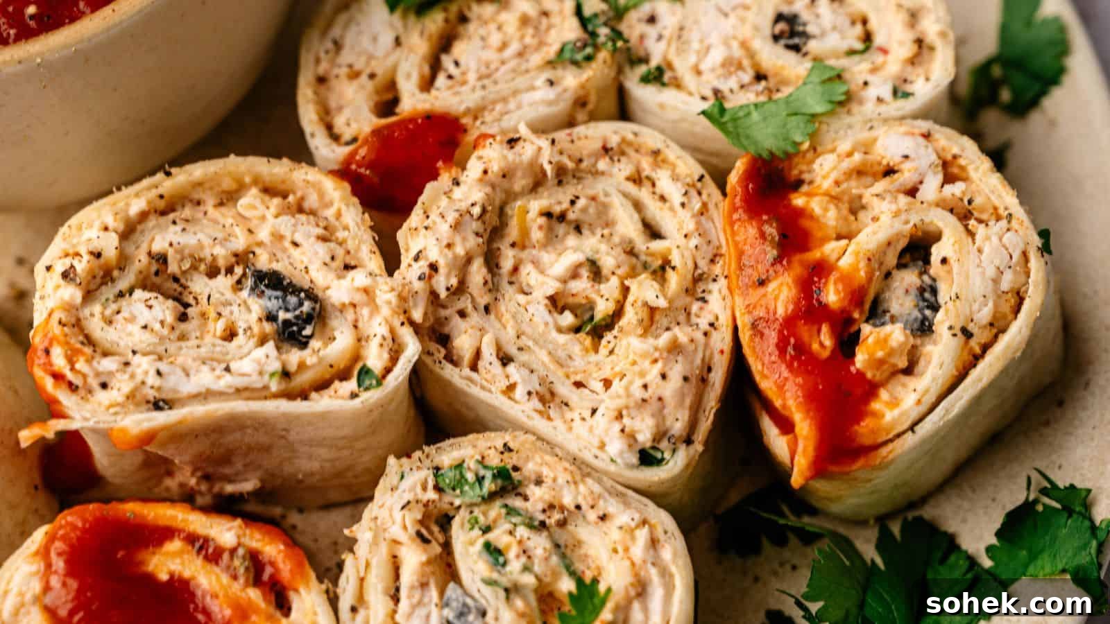 33 Quick Chicken Dinners for Busy Nights When You’re Tired but Hungry 25 Close-up of several tortilla pinwheel roll-ups filled with shredded chicken, herbs, and sauce, garnished with cilantro.