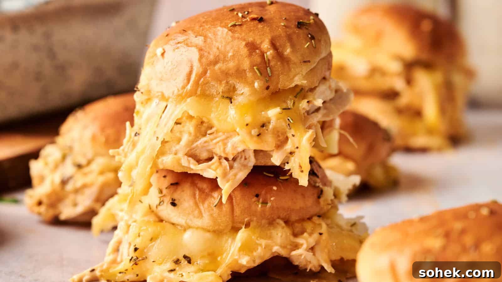 33 Quick Chicken Dinners for Busy Nights When You’re Tired but Hungry 30 A stack of slider sandwiches filled with shredded chicken and melted cheese, topped with herbs, on a light surface.