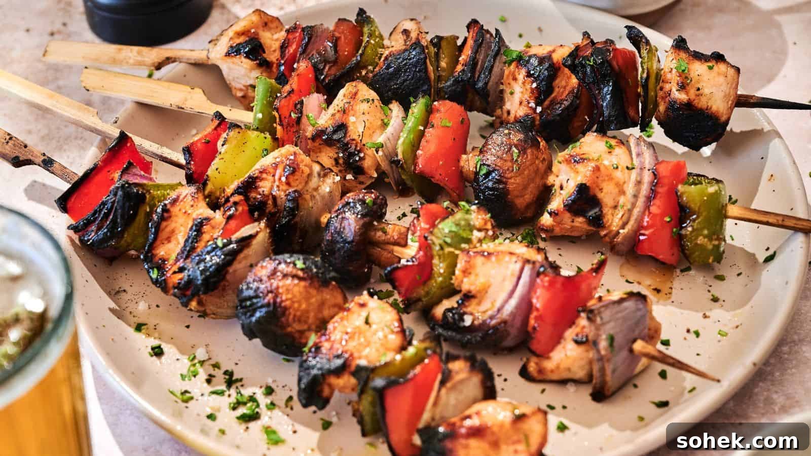 33 Quick Chicken Dinners for Busy Nights When You’re Tired but Hungry 34 Grilled chicken skewers with red bell peppers, green bell peppers, and onions are served on a white plate, garnished with chopped herbs.