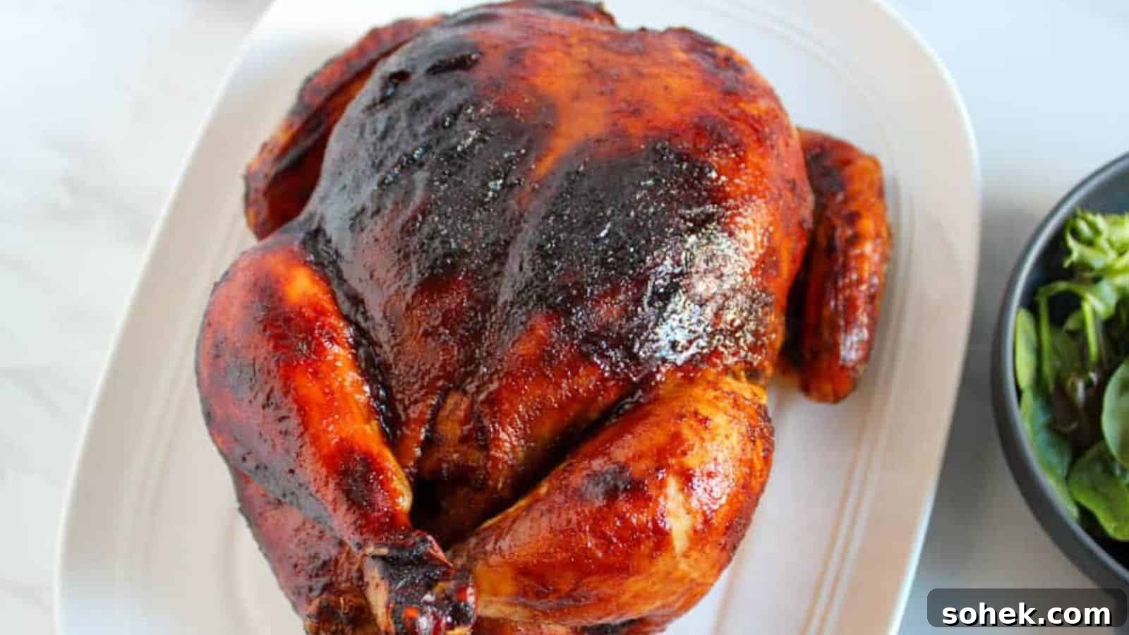33 Quick Chicken Dinners for Busy Nights When You’re Tired but Hungry 6 Roasted chicken with a crispy, golden-brown skin on a white plate, served with a side of greens in a black bowl.