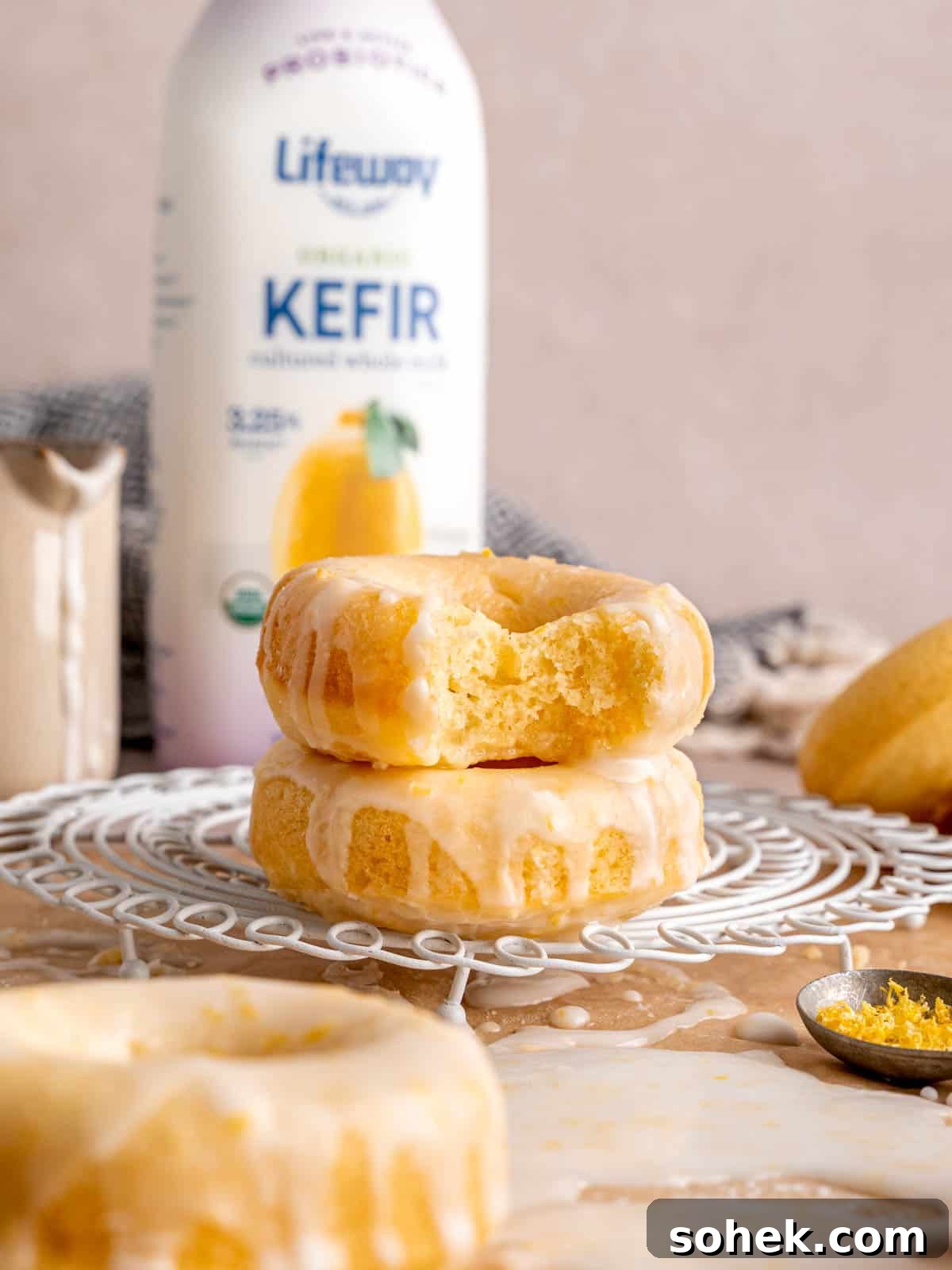Iced lemon donuts stacked in front of a bottle of Lifeway Lemon Kefir.