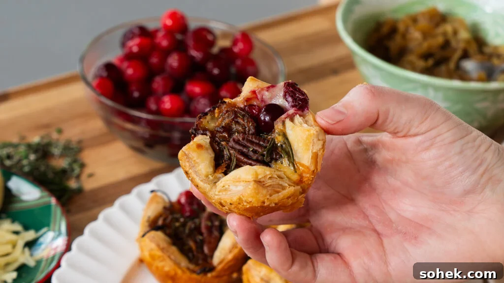 Brie and Caramelized Onion Puff Pastry Bites with Rosemary 9 Someone holding a brie puff pastry bite.