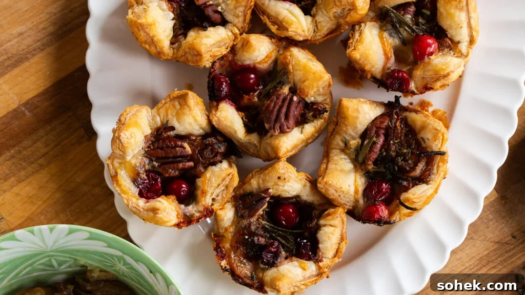 Brie and Caramelized Onion Puff Pastry Bites with Rosemary 10 Brie puff pastry bites on a white serving platter.
