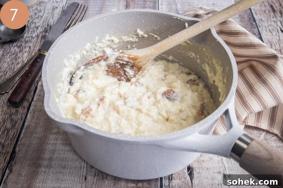 Classic Gluten-Free Bread Sauce Recipe for Roast Dinners 10 bread sauce in saucepan with wooden spoon.