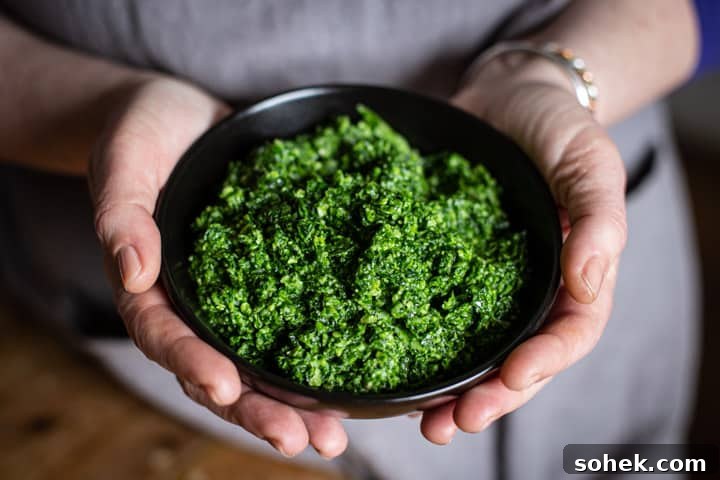 Wild Garlic Pesto: Simple Spring Sauce Recipe for Pasta & Bread 9 woman in grey holding a black bowl or bright green homemade ramson pesto