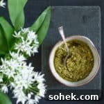 Wild Garlic Pesto: Simple Spring Sauce Recipe for Pasta & Bread 10 slate background with bowl of homemade Ramsons Pesto and some ramson flowers