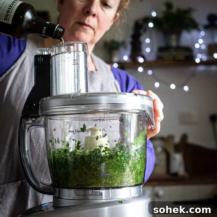 Wild Garlic Pesto: Simple Spring Sauce Recipe for Pasta & Bread 6 woman in grey pouring olive oil into a food processor to make fresh pesto