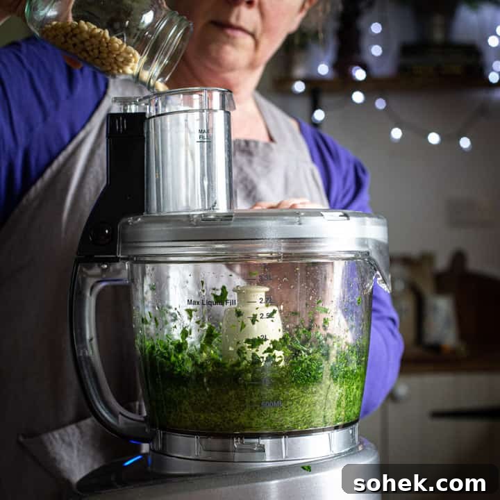 Wild Garlic Pesto: Simple Spring Sauce Recipe for Pasta & Bread 7 woman in grey pouring nuts into a food processor to make pesto