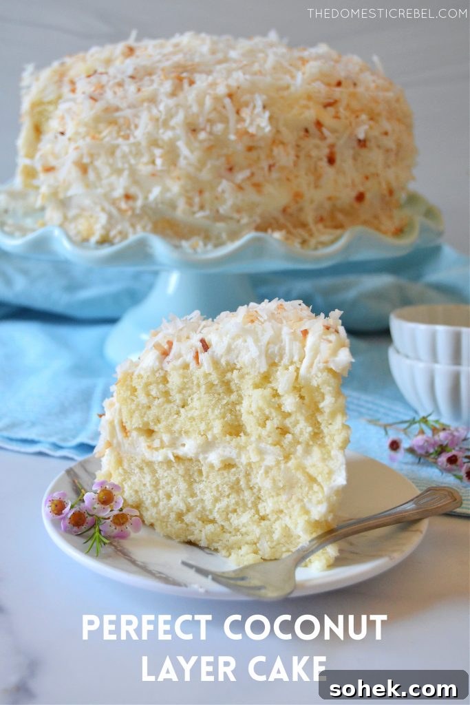 coconut layer cake slice on a white plate with flowers and a fork