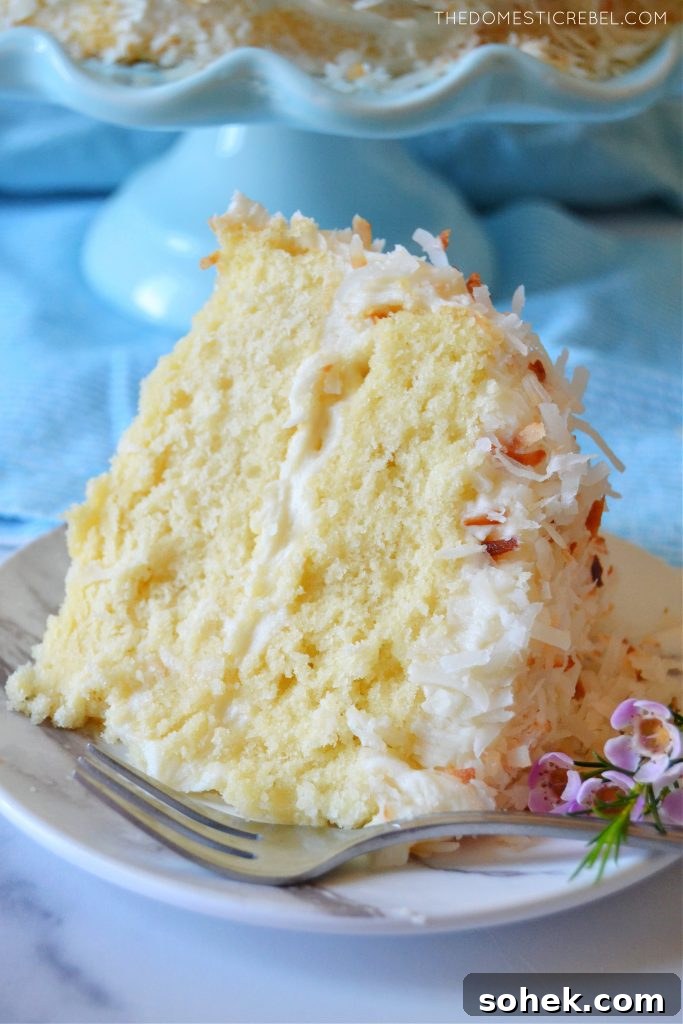 coconut layer cake slice with flowers and a fork on a plate