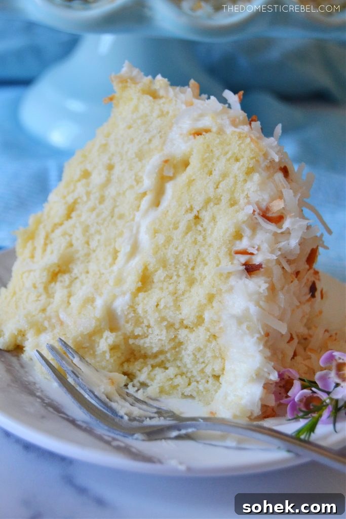 closeup of a slice of coconut layer cake with bite missing