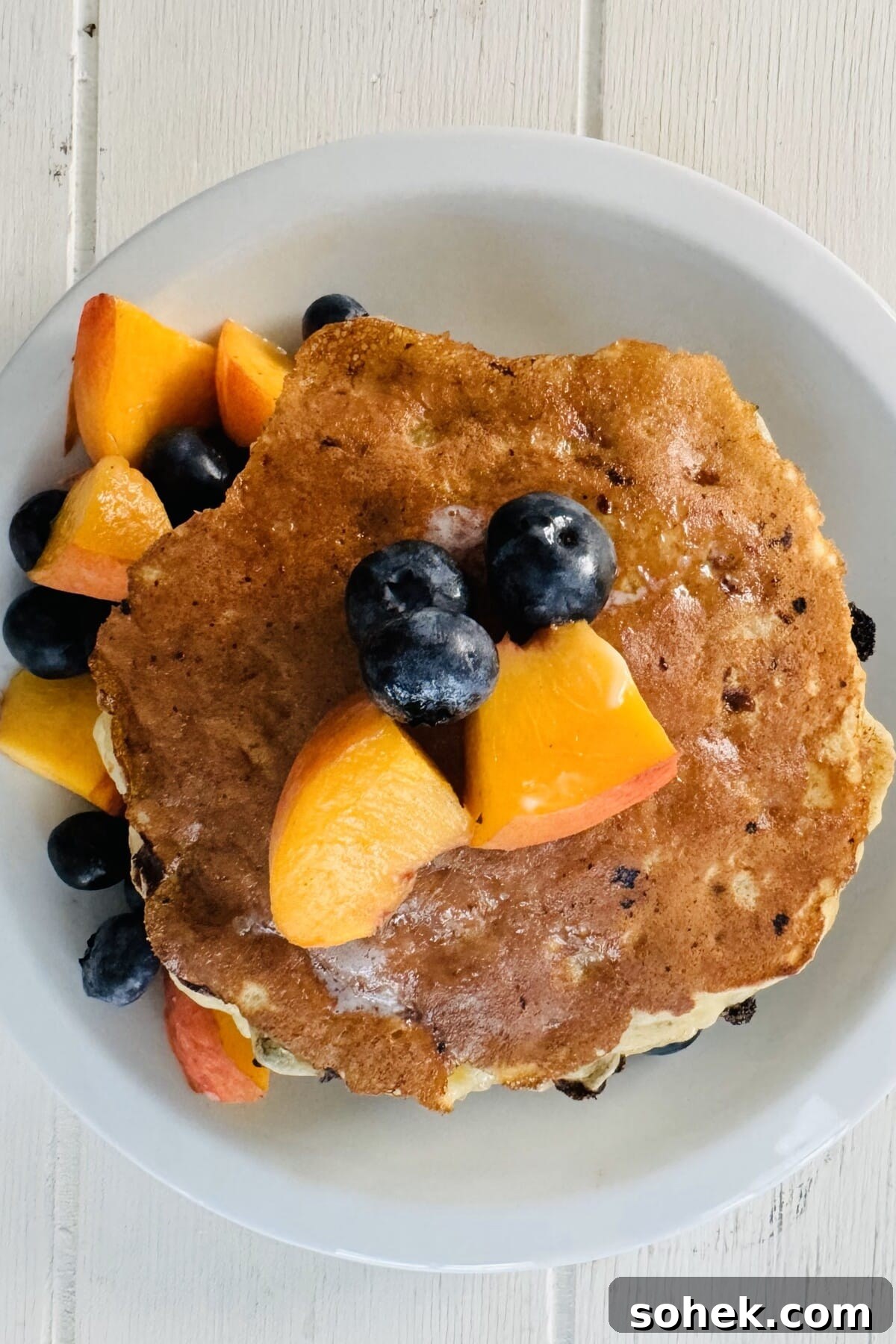 Fluffy Banana and Cottage Cheese Pancakes for Protein-Packed Breakfast 13 A pancake with cut up peaches and blueberries.
