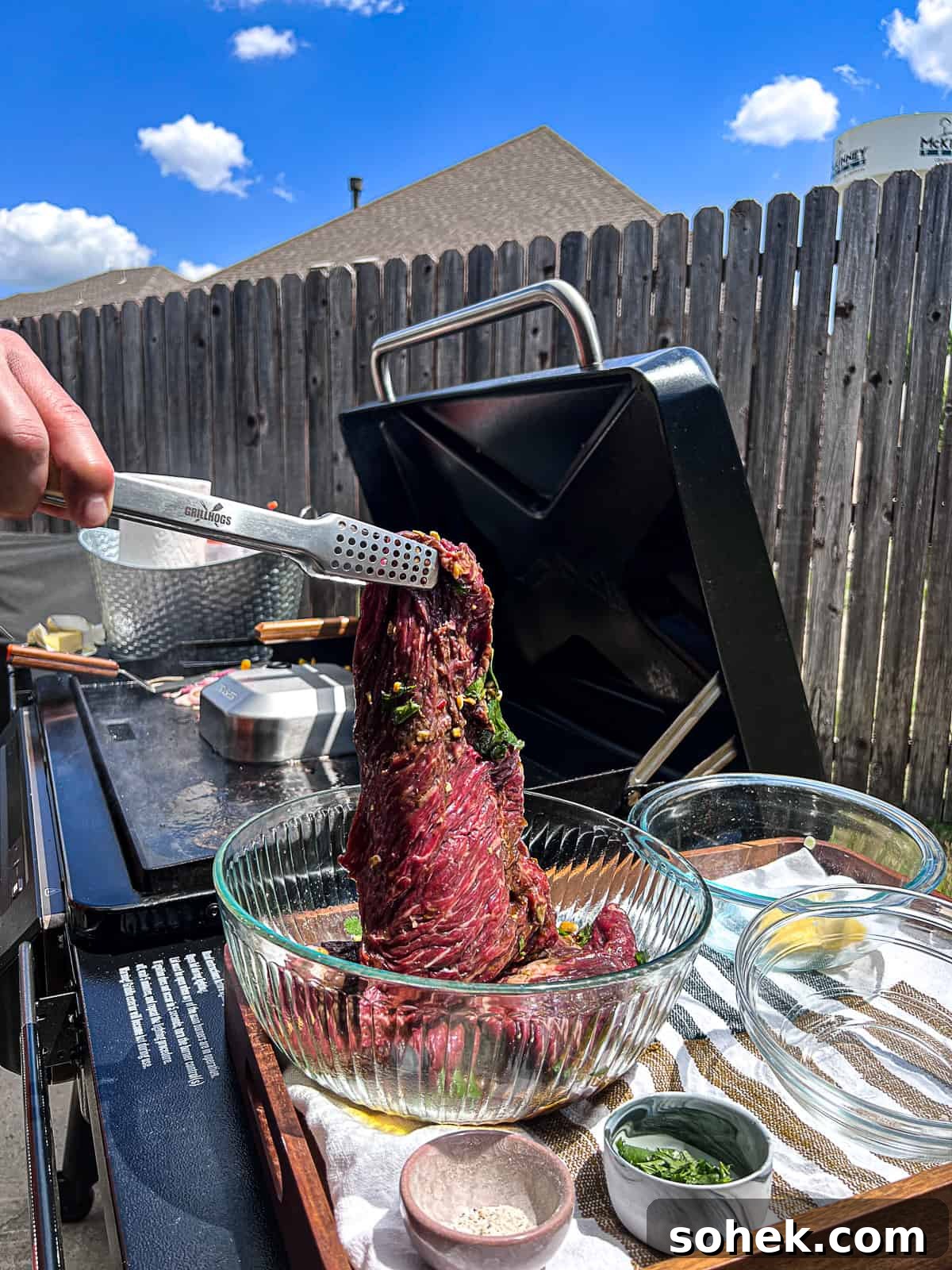 Zesty Flap Steak Marinade for Juicy, Flavor-Packed Grilling 4 Tongs pulling tenderized flap meat out of marinade next to Traeger Flatrock Griddle