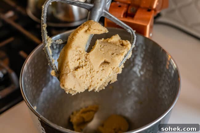 butter, sugar, and peanut butter mixed together in the bowl of a stand mixer.