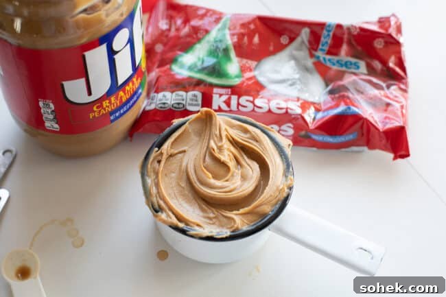 cup measurement full of creamy peanut butter, peanut butter container, and bag of Hershey's kisses.