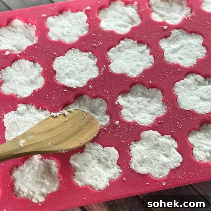 Tea Tree Acne Facial Tabs — Lush-Inspired Acne Treatment 7 pressing mixture for tea tree essential oil facial steamer tabs into flower shaped silicone molds with wooden spoon