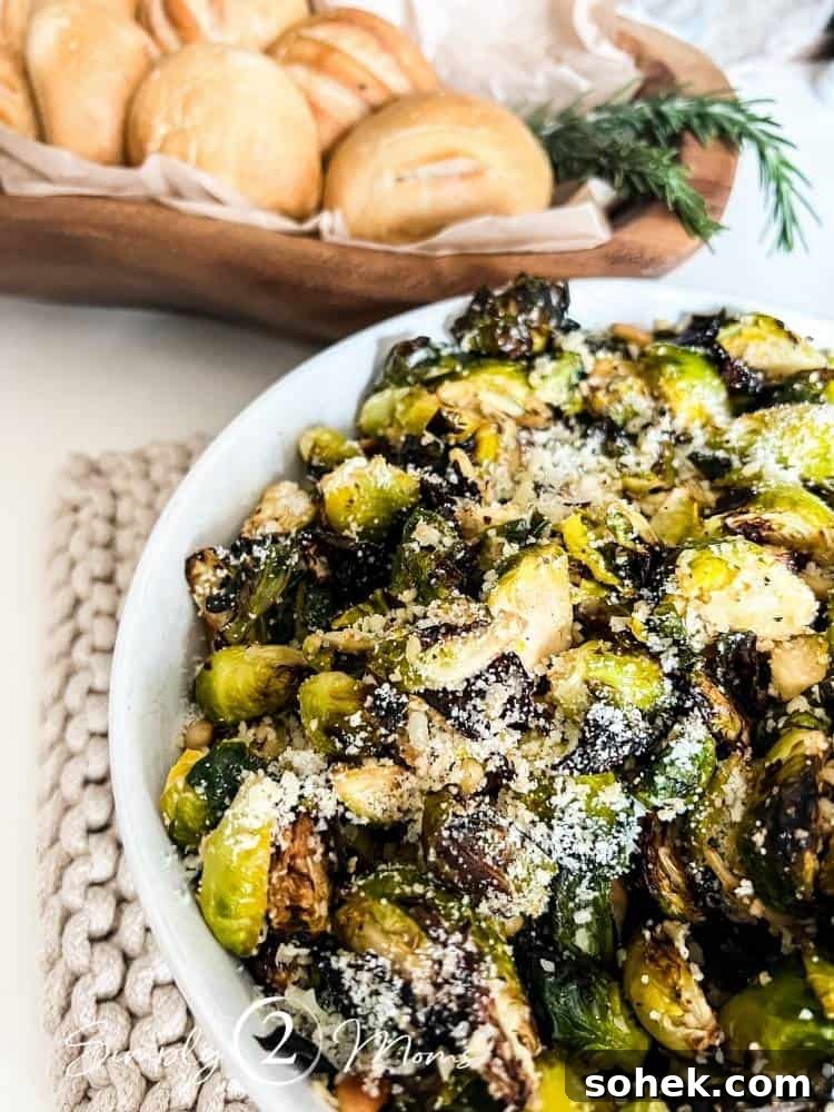 Stunning Italian Dinner Party Menu Ideas to Impress Your Guests 7 Bowl of crispy air fryer Parmesan Garlic Brussels Sprouts on a table next to a wooden bowl filled with fresh dinner rolls.