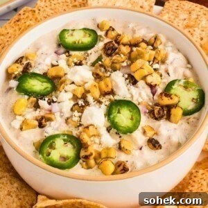 Creamy Mexican corn dip in a white bowl, surrounded by tortilla chips for dipping.