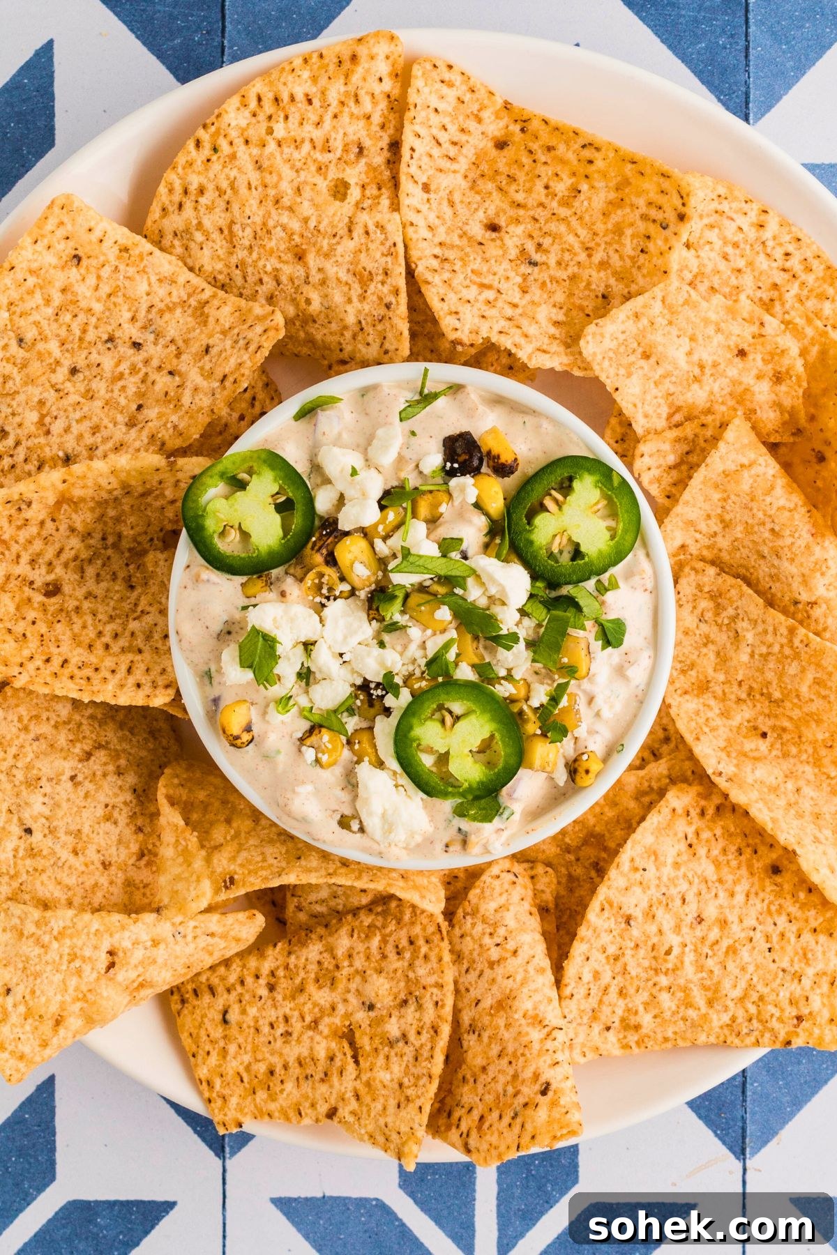 Mexican street corn dip in a small bowl surrounded by tortilla chips. 