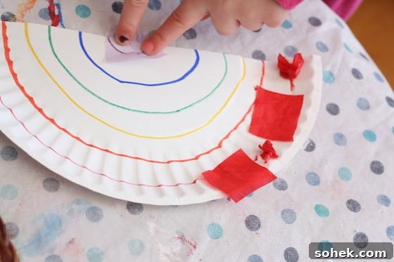 Child gluing tissue paper onto paper plate