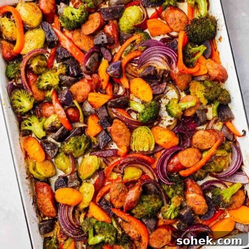 Sheet Pan Sausage and Roasted Vegetables with Herbs 11 An overhead view of roasted sausage and vegetables on a white sheet pan after baking.