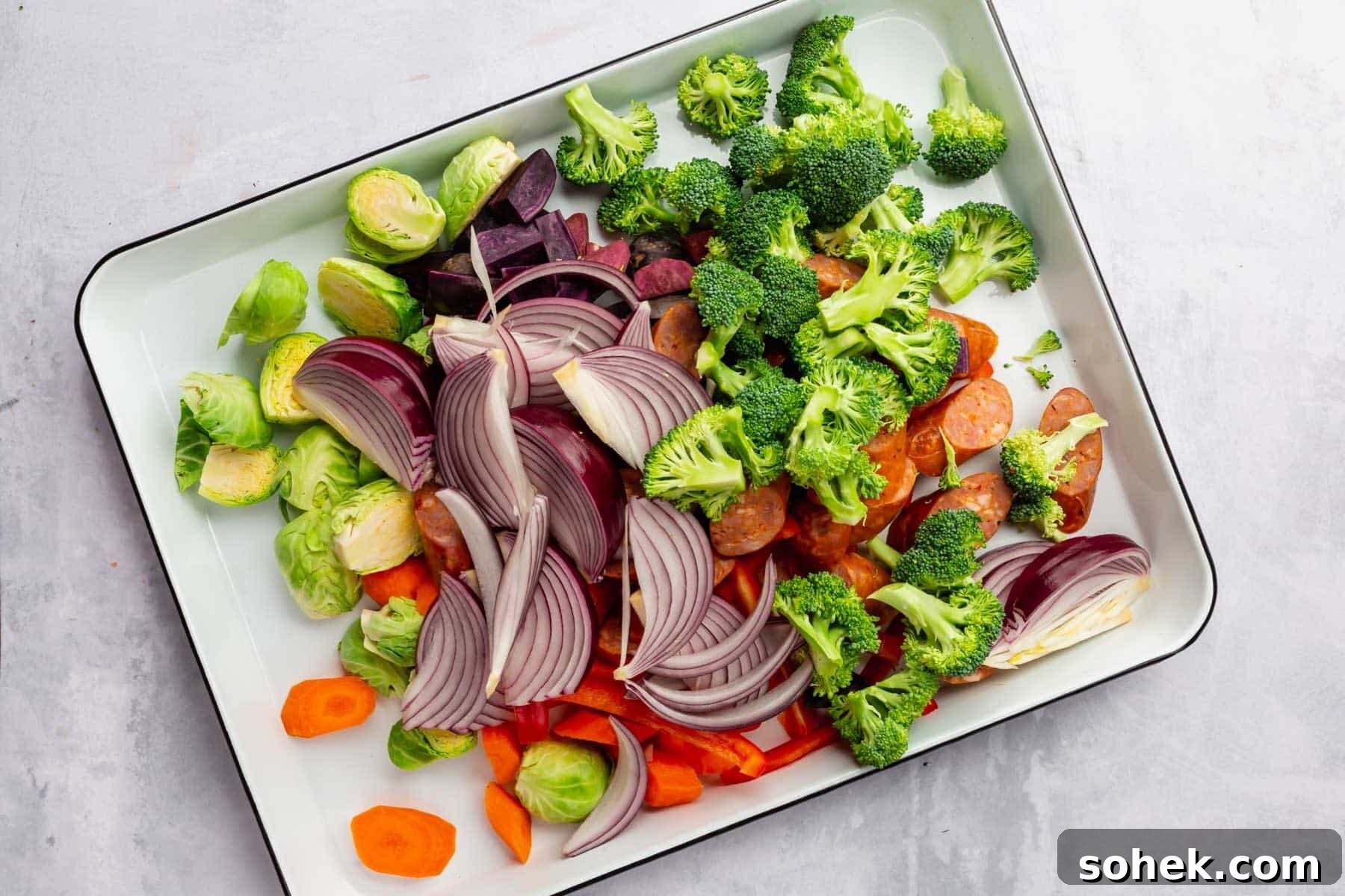 Sheet Pan Sausage and Roasted Vegetables with Herbs 12 Raw vegetables combined on a sheet pan before baking.
