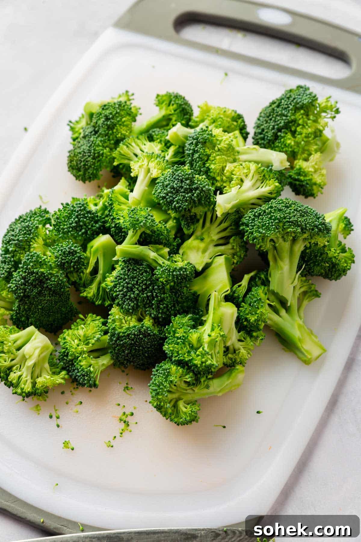 Sheet Pan Sausage and Roasted Vegetables with Herbs 8 Broccoli cut into small florets on a white cutting board.