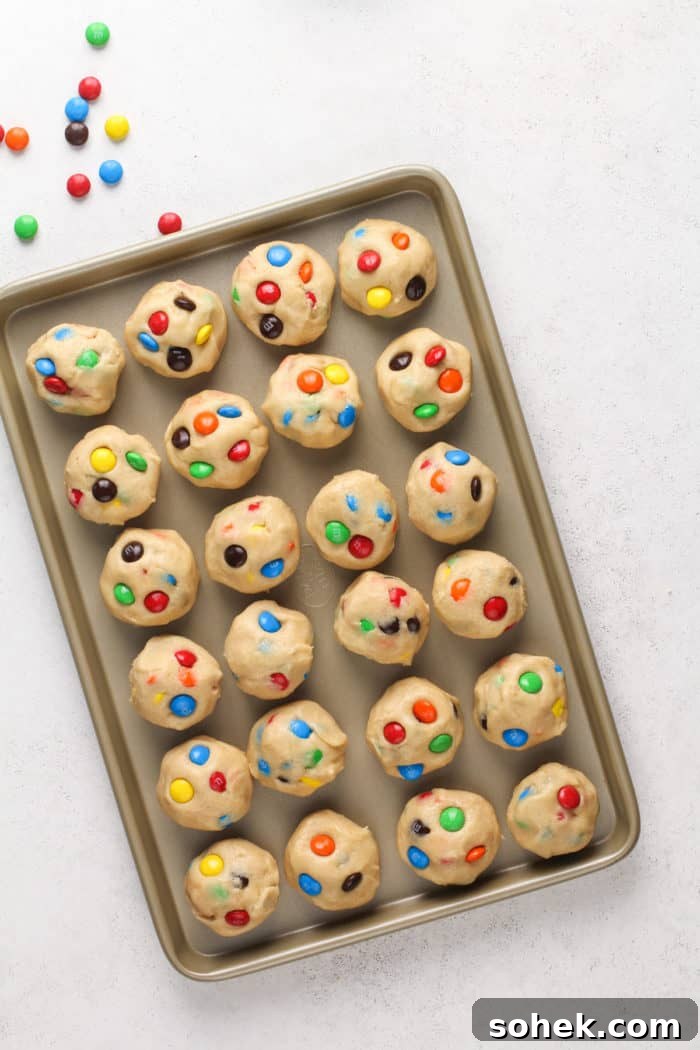 Chewy M&M Cookies Recipe for Perfect Chocolate Crumble 7 Balls of m&m cookie dough set on a baking sheet to chill.