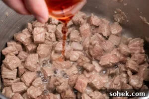 Greggs-Style Steak Bake Recipe: How to Make It at Home 9 Pouring red wine vinegar over the chopped beef cooking in a pot