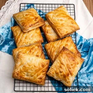 Greggs-Style Steak Bake Recipe: How to Make It at Home 4 Eight cooked steak bakes stacked up on top of each other on a wire rack with a blue and white cloth under the wire rack