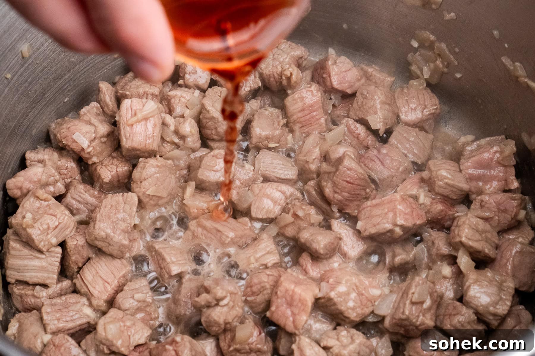 Greggs-Style Steak Bake Recipe: How to Make It at Home 28 Pouring red wine vinegar over the chopped beef cooking in a pot