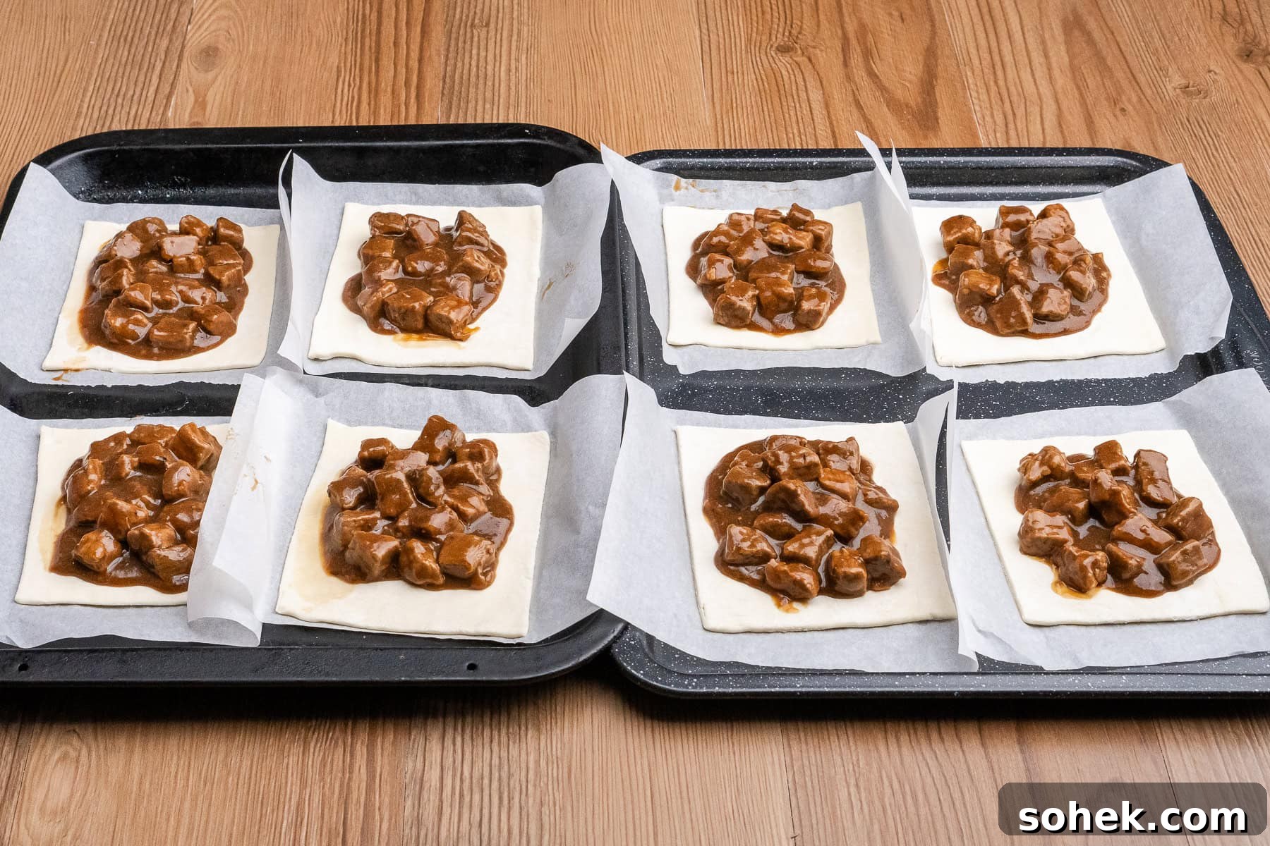 Greggs-Style Steak Bake Recipe: How to Make It at Home 35 Eight squares of puff pastry on parchment paper filled with steak filling on two baking trays