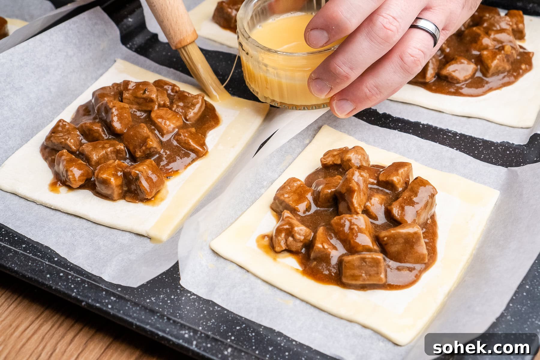 Greggs-Style Steak Bake Recipe: How to Make It at Home 36 Egg washing the edges of the puff pastry squares filled with steak bake recipe filling