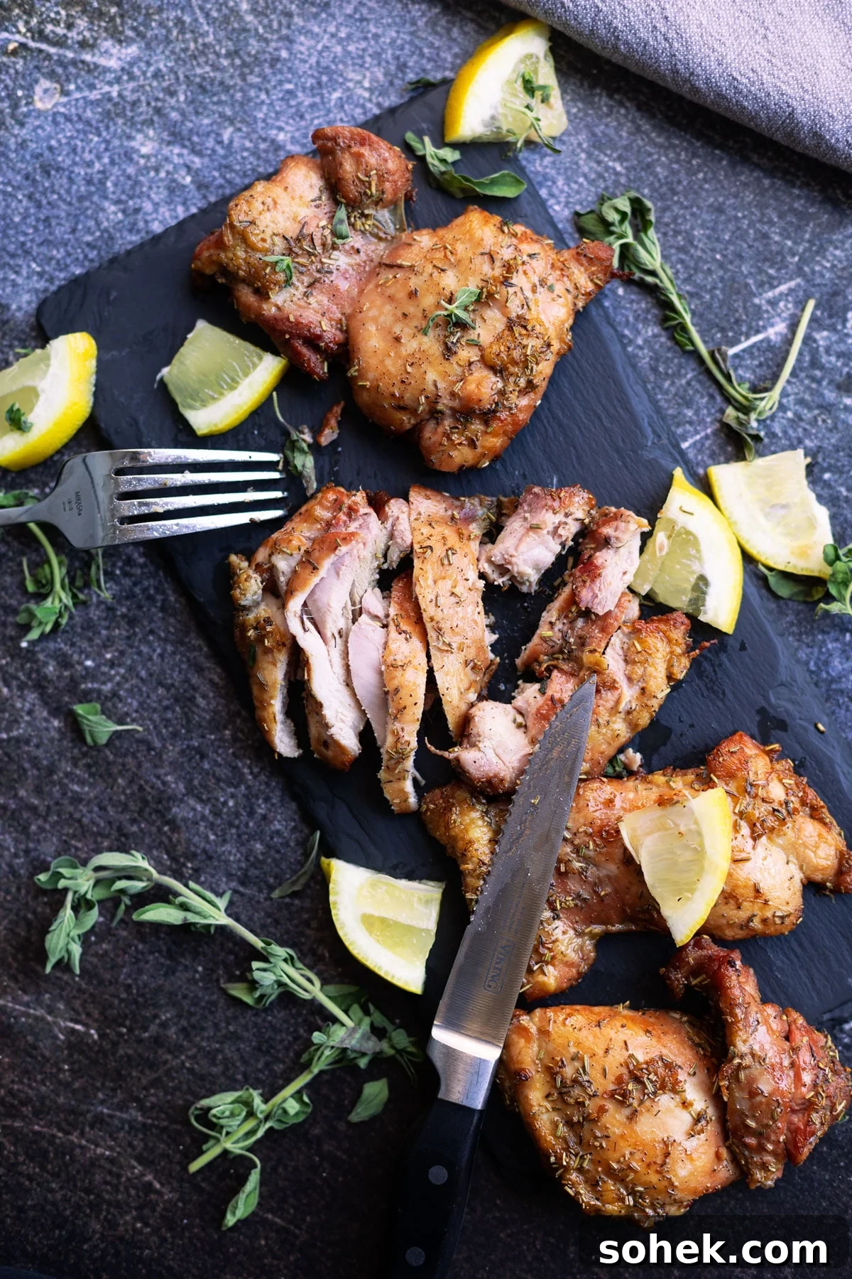 Juicy Smoked Chicken Thighs with Crispy Skin Recipe 3 Sliced smoked chicken thighs on a cutting board topped with lemon.
